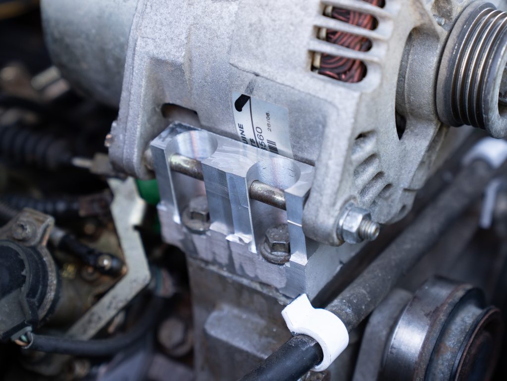 An engine bay of a military Land Rover showing a 3D printed metal mount for its alternator. Photo via the British Army.